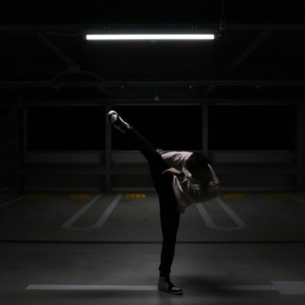 Man performing a dynamic bodyweight exercise in a modern, dark environment.